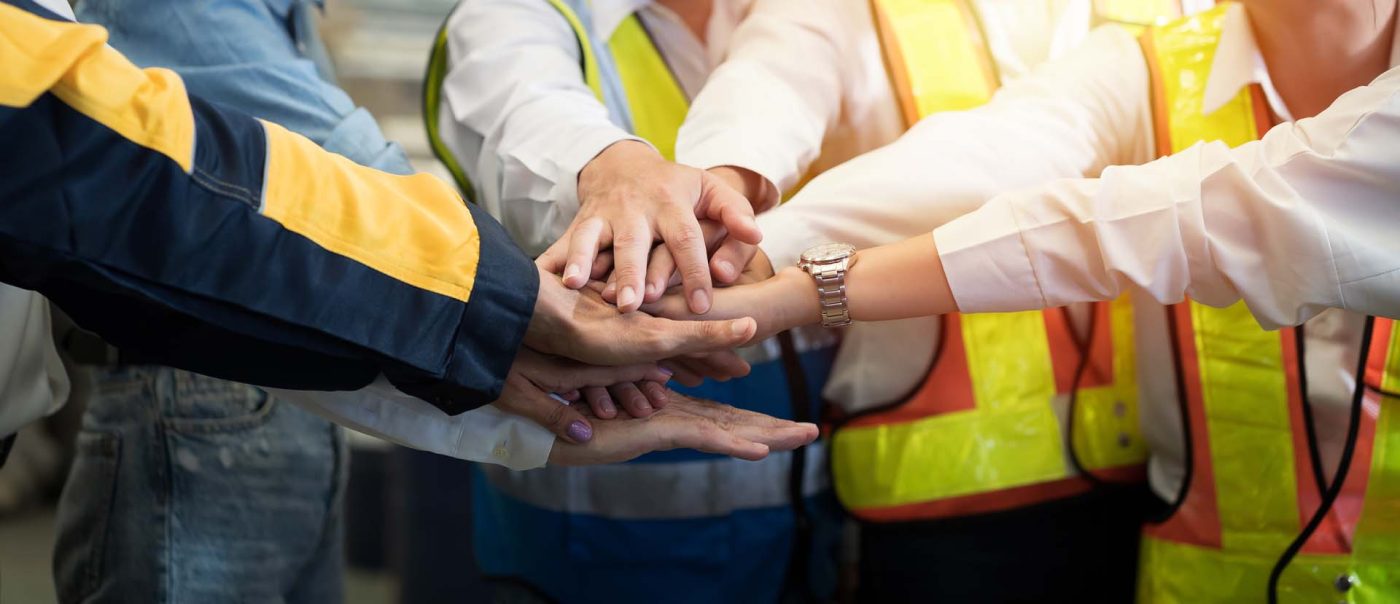Group of male and female factory workers standing putting their